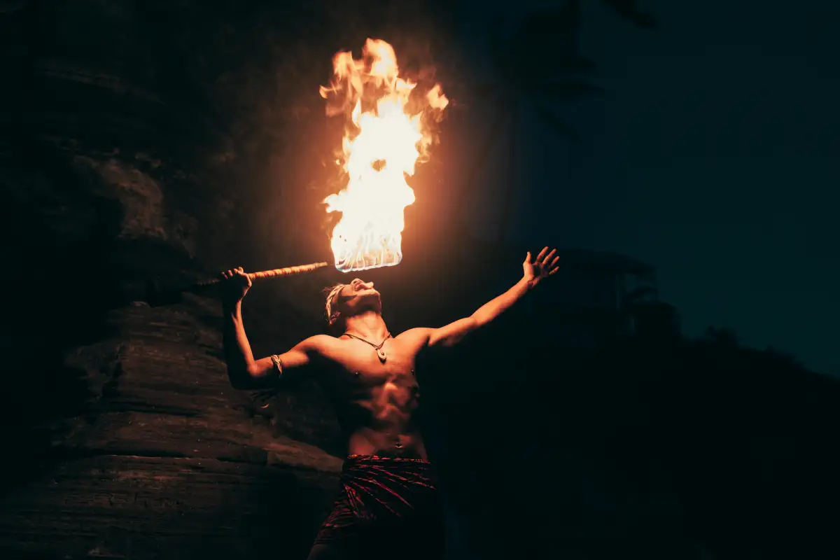 A man with a fire torch at a lively luau on the Big Island.