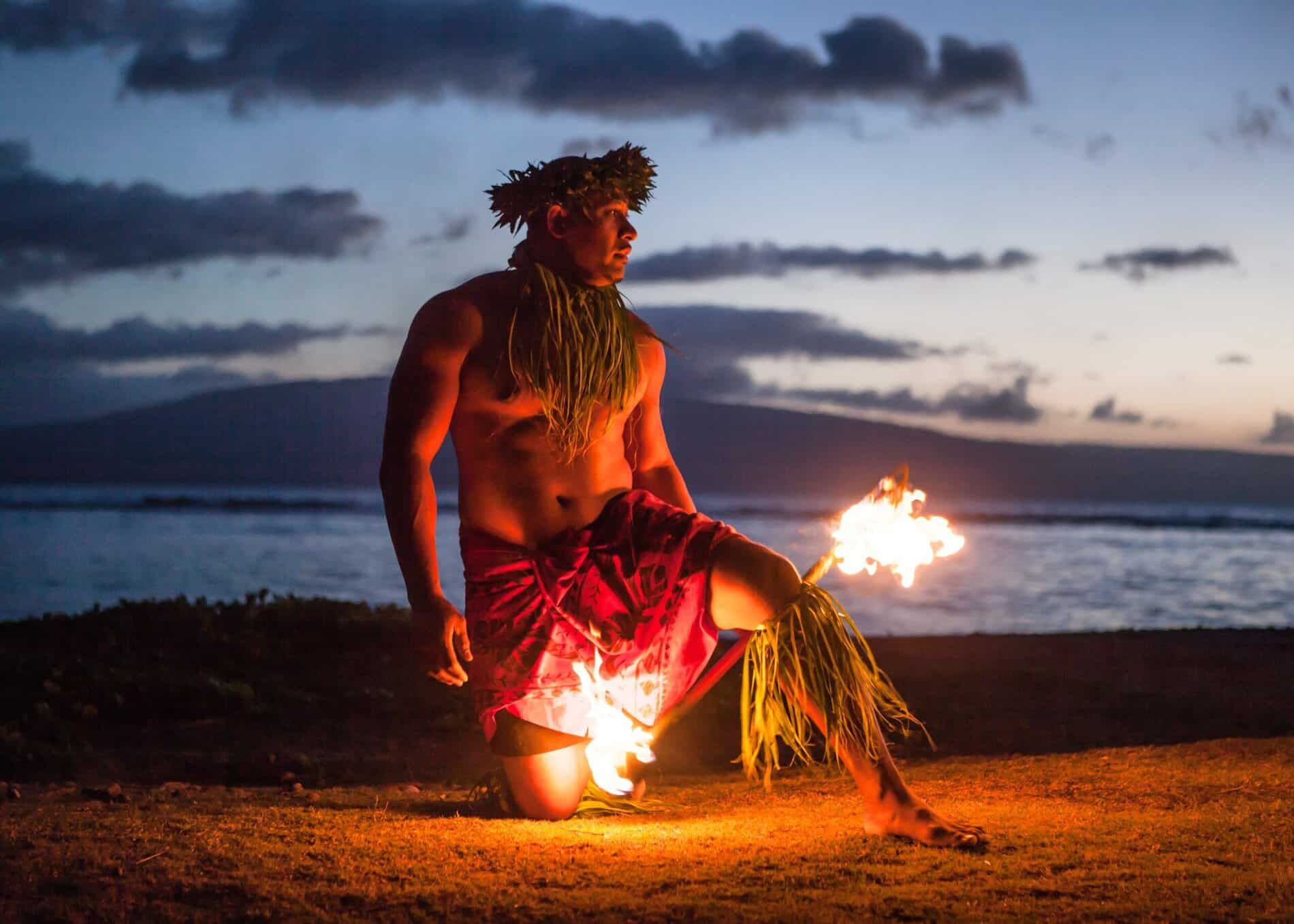 Man dances with fire during a vibrant Maui luau event.