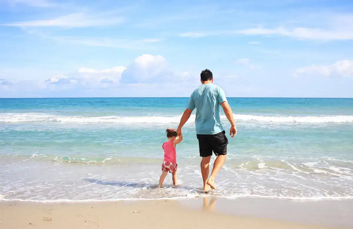 Father and his little daughter stroll on the beach making memories on their Big Island trip.