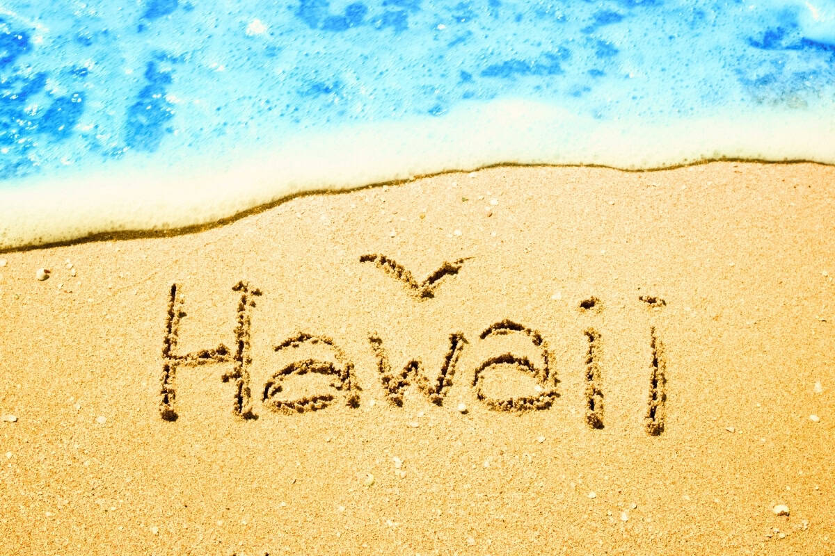 Sand on a Hawaii beach with the word "Hawaii" written in it, symbolizing eco-friendly travel tips for the Big Island.