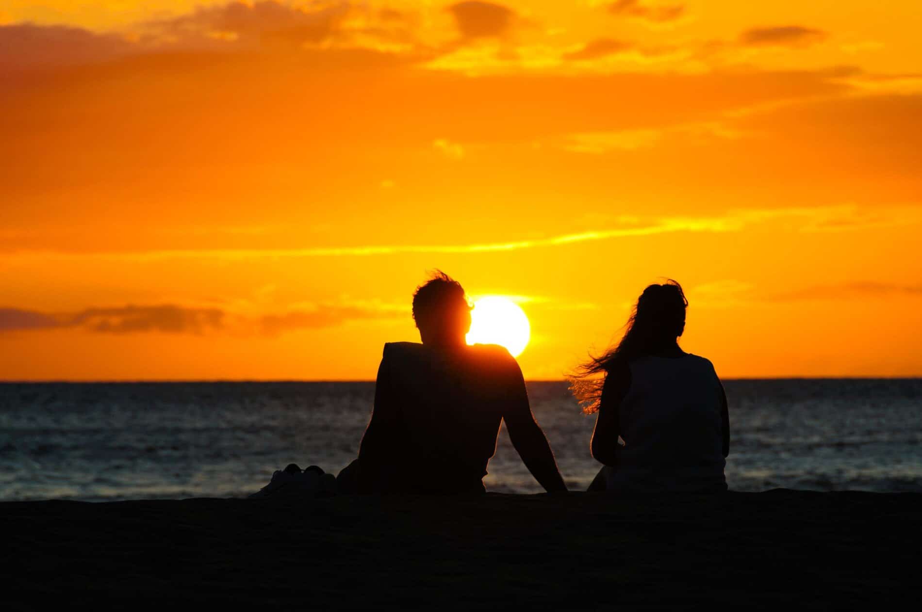 A couple enjoying a romantic moment on the beach, enjoying the stunning Maui sunset.