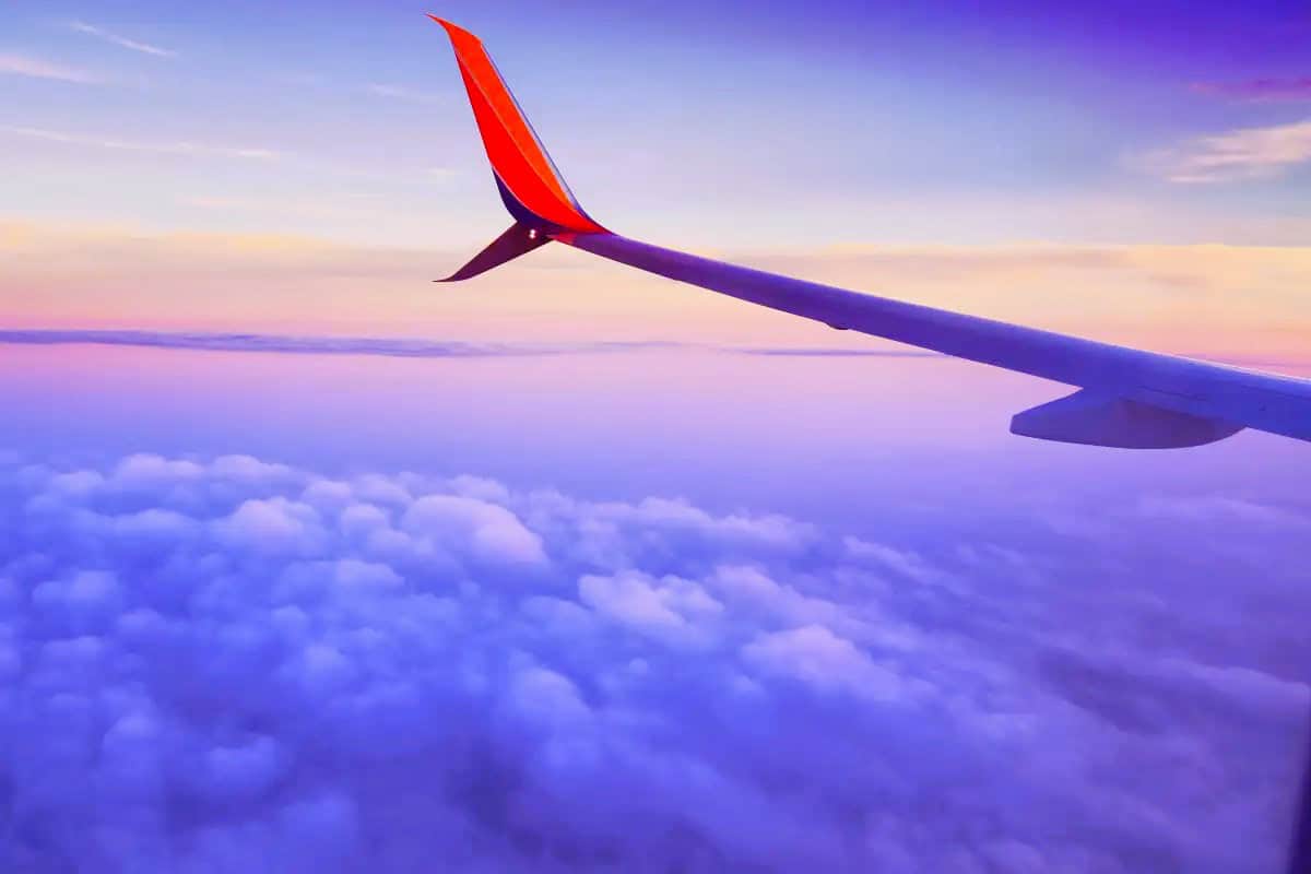close-up of an airplane wing flying high over a sea of clouds, capturing the thrill of visiting the Big Island for the first time.