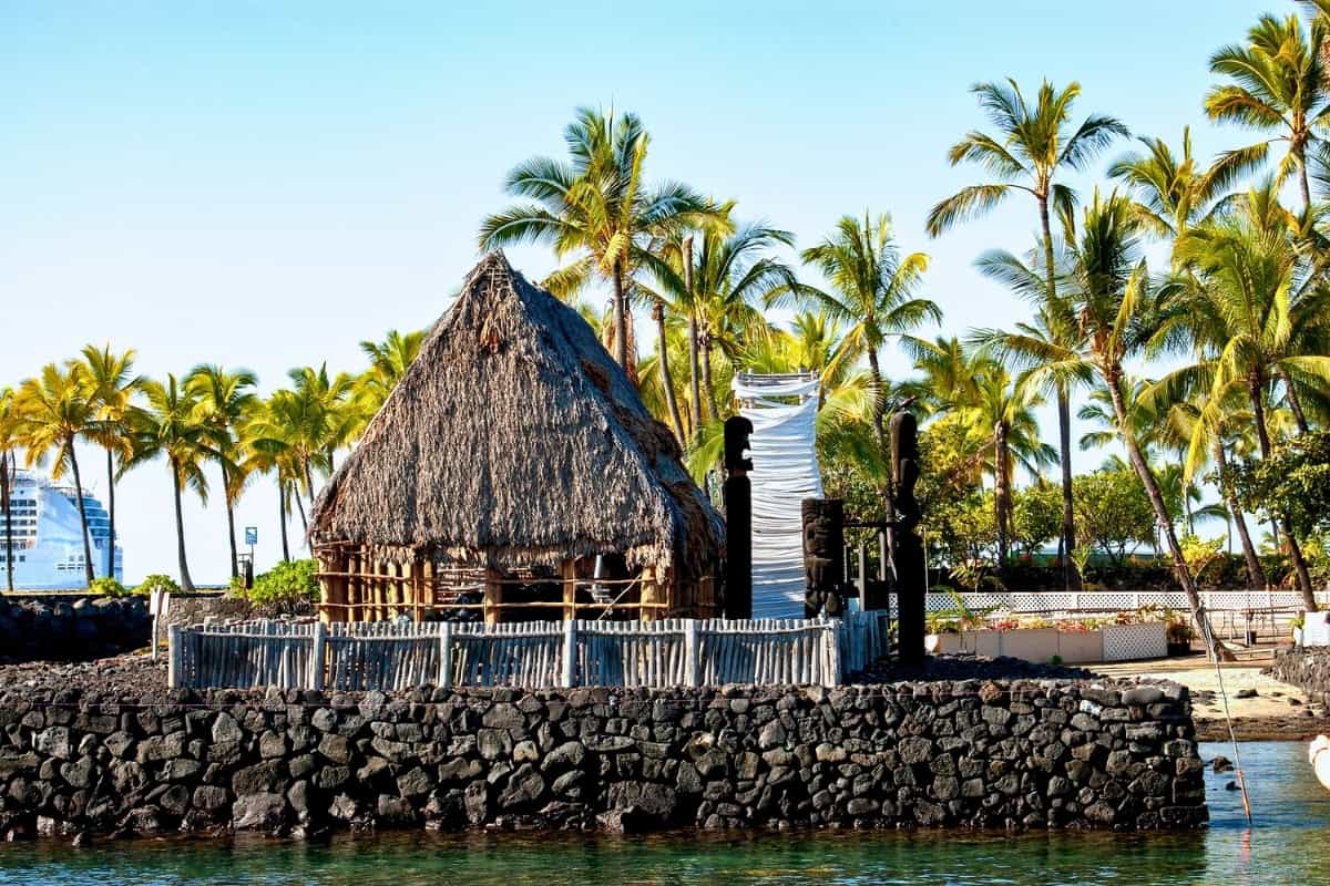 Ahuʻena Heiau, a restored Hawaiian temple, with a thatched hut by the water's edge in Kailua-Kona, Big Island.