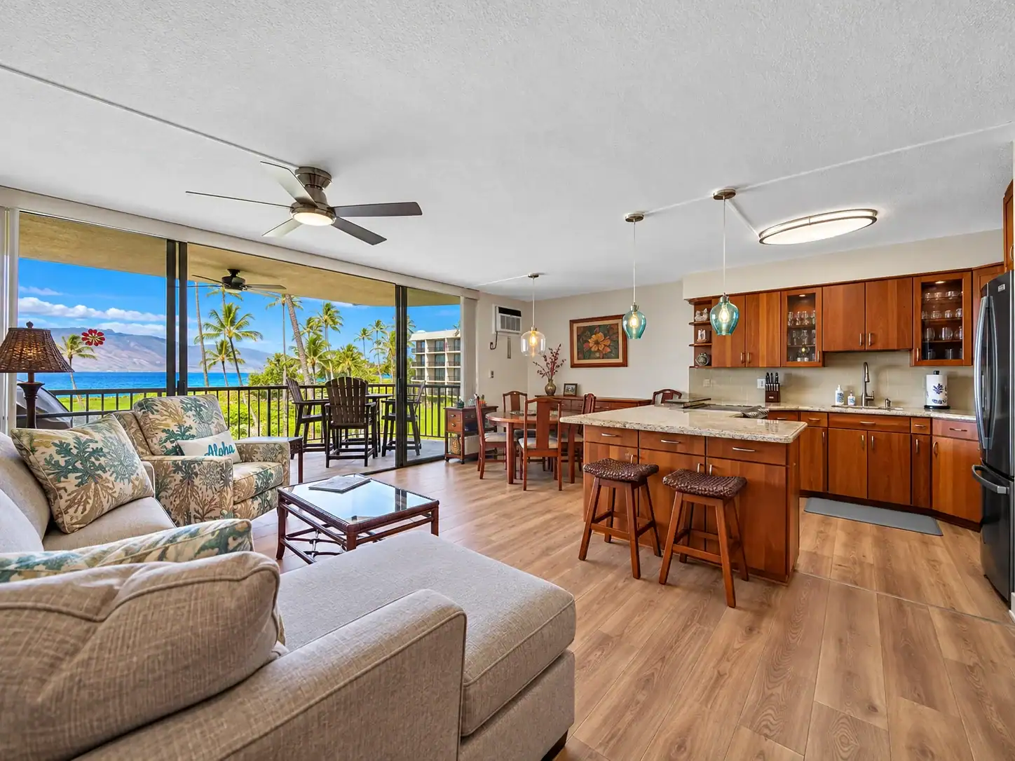 Spacious Hawaii vacation rental with an open-plan living room, full kitchen, dining area, and ocean-view lanai.